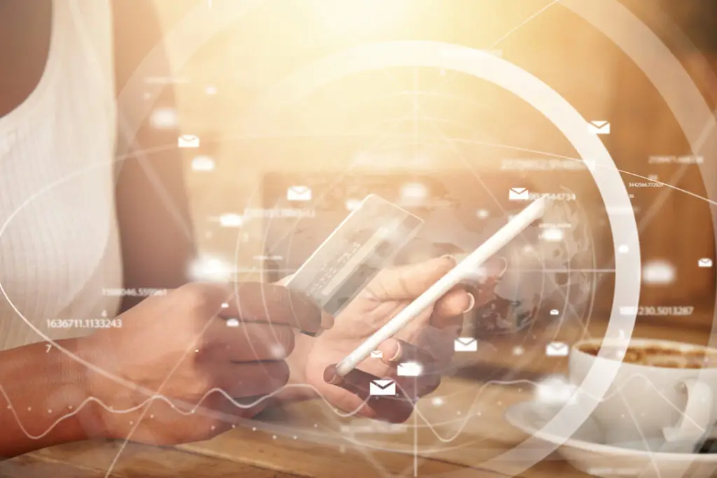 Hands holding a credit card and a smartphone over a glowing network of email icons and data charts